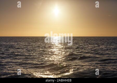 Setting sun over the ocean reflected in water, natural background. Stock Photo