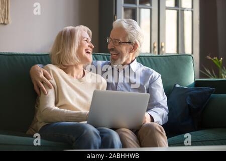 Laughing elderly couple having fun watching comedy on laptop Stock Photo