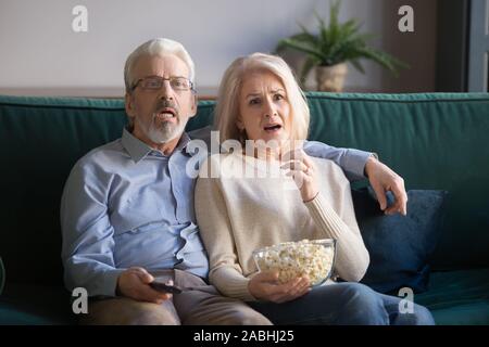 Mature couple sitting on couch watching drama movie Stock Photo