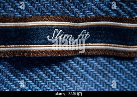 Label on a Blue Shirt Indicating the Size of Clothes- Slim Fit. Blue Garment Background Stock Photo