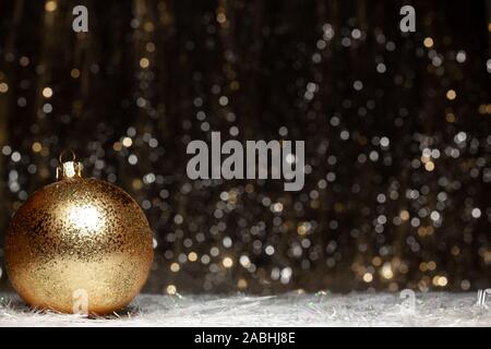 Christmas decorations composition view of gold evening ball with gold glitter on it of the left site on dark background with silver and gold colors bo Stock Photo