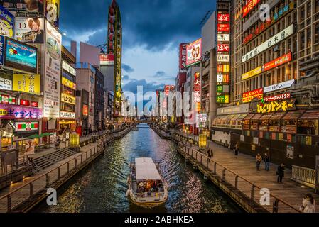 Osaka, Japan - March 21, 2017: Beautiful dusk light and neon lighting on a canal with a boat and  few people in  Dotonbori, Osaka Stock Photo