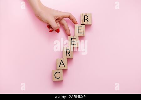 Woman hand climbing on career ladder made of wooden cubes. Self realization concept. Stock Photo