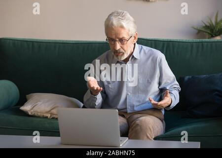 Elderly man makes video call talking looking at computer screen Stock Photo