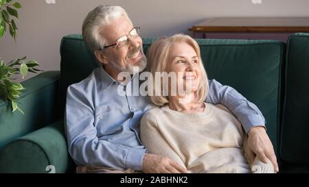 Couple of elderly retirees embracing resting on looking away Stock Photo