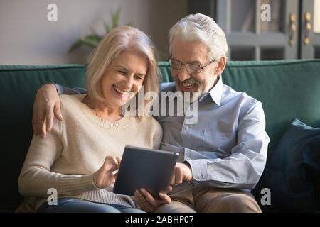 Cheerful elderly spouses having fun using digital tablet Stock Photo