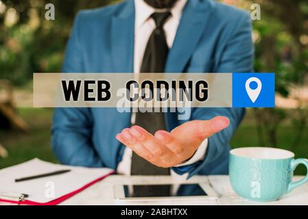 Writing note showing Web Coding. Business concept for work involved in developing a web site for the Internet Man in front of table. Mobile phone and Stock Photo