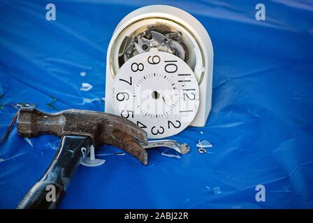 hammer with pieces of smashed alarm clock on blue plastic Stock Photo