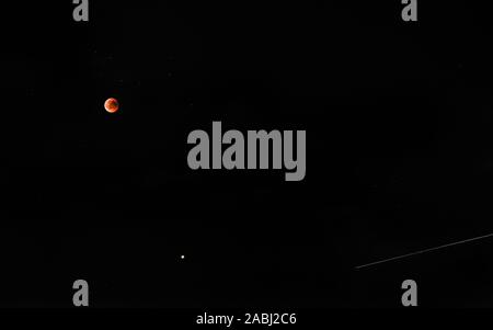 Bloody red moon eclipse with comet trail on starry black sky background Stock Photo