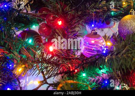 Colourful fairy lights and baubles decorate a Christmas tree. Stock Photo
