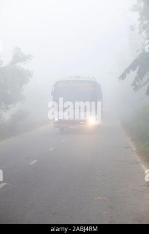 Bangladesh – January 06, 2014: On a foggy winter morning, a bus is passing through the foggy streets and slows traffic at Ranisankail, Thakurgaon. Stock Photo