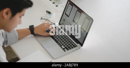 Cropped shot of young professional UI web developer working on smartphone application with laptop computer Stock Photo