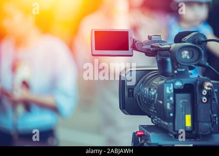 Video camera camcorder operator working at live event broadcasting blue color tone. Stock Photo