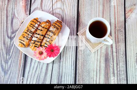 Trieclera and flower buds lie on a plate near a mug of tea on a wooden table. Close-up. Stock Photo