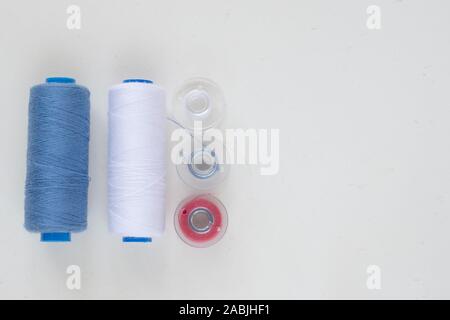 Sewing accessories on a light background close-up. Multi-colored spools of thread Stock Photo