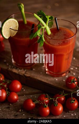 bloody mary cocktail in glasses on wooden background with salt, pepper, tomatoes and celery Stock Photo