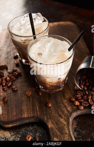 white russian cocktail in glasses with straws on wooden board with coffee grains Stock Photo