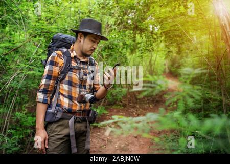 man traveler with backpack using smartphone in the natural forest Stock Photo