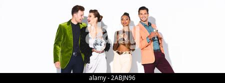 panoramic shot of happy and stylish multicultural friends holding champagne glasses and disco ball on white Stock Photo
