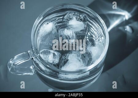 Glass of water with ice on gray background. Healthy drinking water in luxury style in monochrome color. Transparent beverage on dark backdrop. Stock Photo