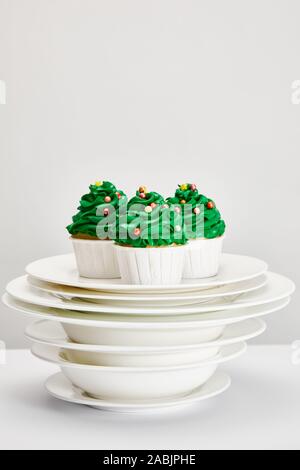 tasty Christmas tree cupcakes on white plates isolated on grey Stock Photo