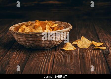 delicious crispy potato chips in wicker basket on wooden table Stock Photo