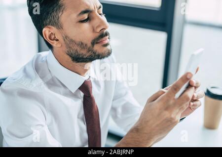 thoughtful businessman using smartphone in office Stock Photo