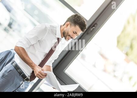 young businessman smiling while looking at papers in office Stock Photo