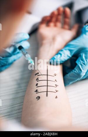 cropped view of allergist holding syringe near woman in clinic Stock Photo