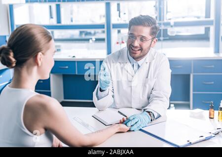 selective focus of happy doctor showing thumb up and holding hand of woman in clinic Stock Photo