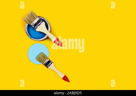 Renovation concept. Yellow background with blue paint jar and two brushes with blue circle. Flat lay, top view, copy space. Stock Photo