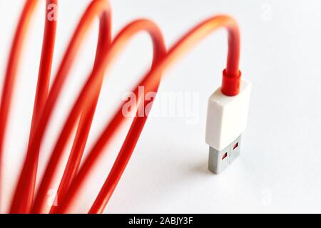 Close-up of red curled USB cable on white background Stock Photo