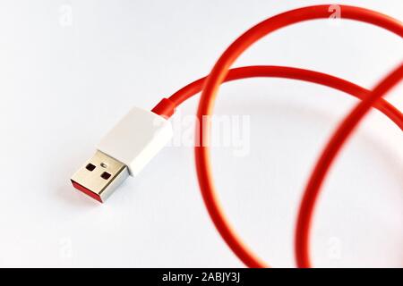 Close-up of red curled USB cable on white background Stock Photo
