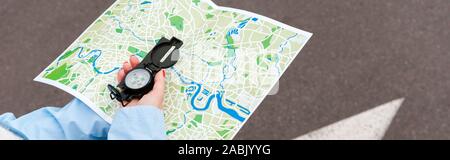 panoramic shot of woman holding map and compass on street Stock Photo