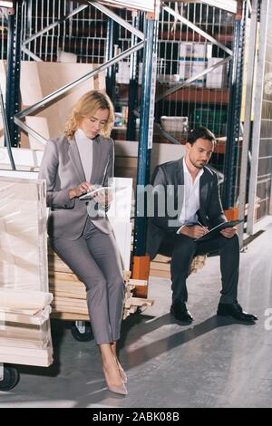 concentrated businesswoman using digital tablet near businessman writing on clipboard Stock Photo