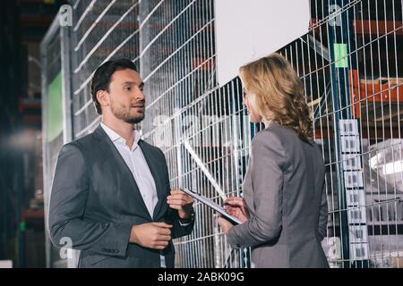 confident business partners talking while standing in warehouse Stock Photo