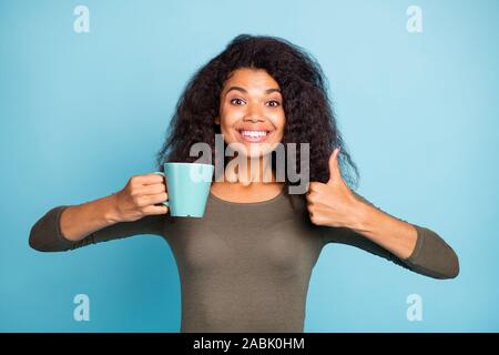 This cafeteria great. Portrait of positive cheerful dark skin girl hold cup hot caffeine beverage show thumb-up give feedback about excellent coffee Stock Photo
