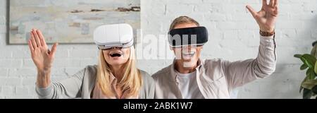 Panoramic shot of exited couple in virtual reality headsets Stock Photo