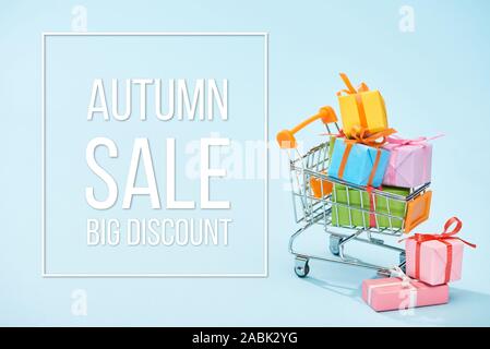 festive wrapped presents in shopping cart on blue background with autumn sale big discount illustration Stock Photo