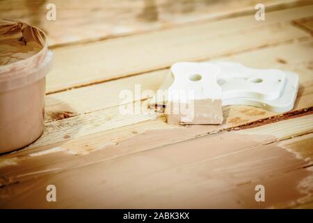 Spatula and putty for puttying wood, on the boards background. Stock Photo