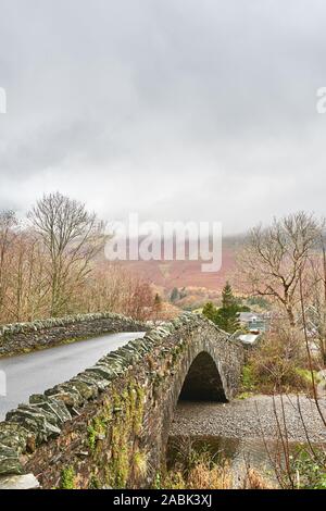 Dry stone bridge over the river Derwent at the village of Grange in the Borrowdale valley, Lake district, Cumbria, England, on a rainy day. Stock Photo