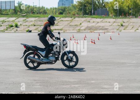 Girl learning to ride a bike at motorcycle racing track. Biker on a motorcycle. Stock Photo