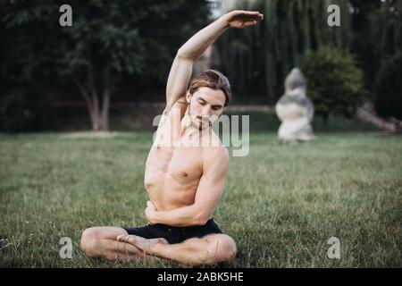 Yoga at park. Bearded man doing yoga in the green park. Concept of a healthy lifestyle. Stock Photo