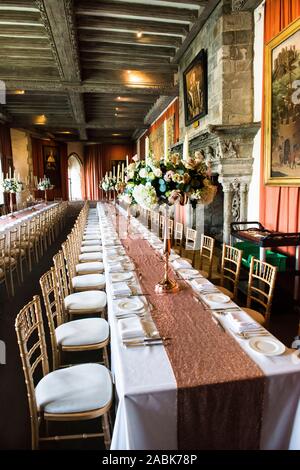 Henry VIII Banqueting Hall, Leeds Castle largest room. Set up with two long tables for a wedding reception. Carved oak ceiling. Carved stone fireplace. Stock Photo
