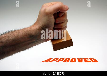 male hand stamping the word approved with a rubber stamp Stock Photo