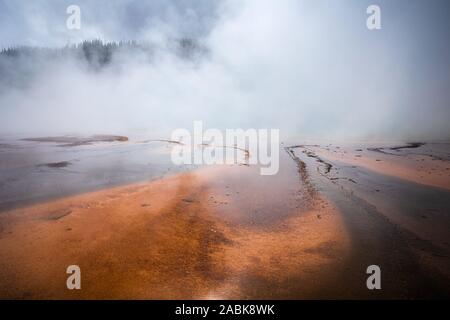 Smoke covered orange pond of Grand Prismatic Spring, famous geyser basin in Yellowstone National Park, Wyoming, USA.