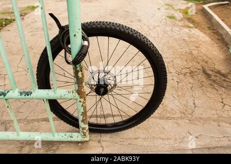 Remains of a stolen bicycle locked to a fence Stock Photo
