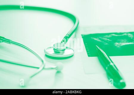 Medical table on green backround with stethoscope, pen and fluorogram, close up. Horizontal image Stock Photo