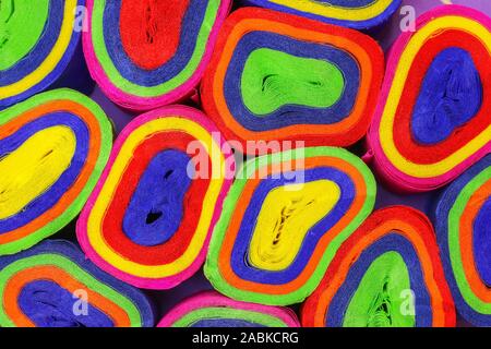 Close up coils of colorful crepe paper bunting of red, orange, yellow, green, blue and pink to make an abstract background Stock Photo