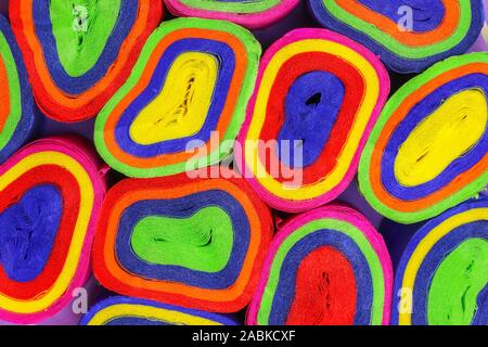 Close up coils of colorful crepe paper bunting of red, orange, yellow, green, blue and pink to make an abstract background Stock Photo